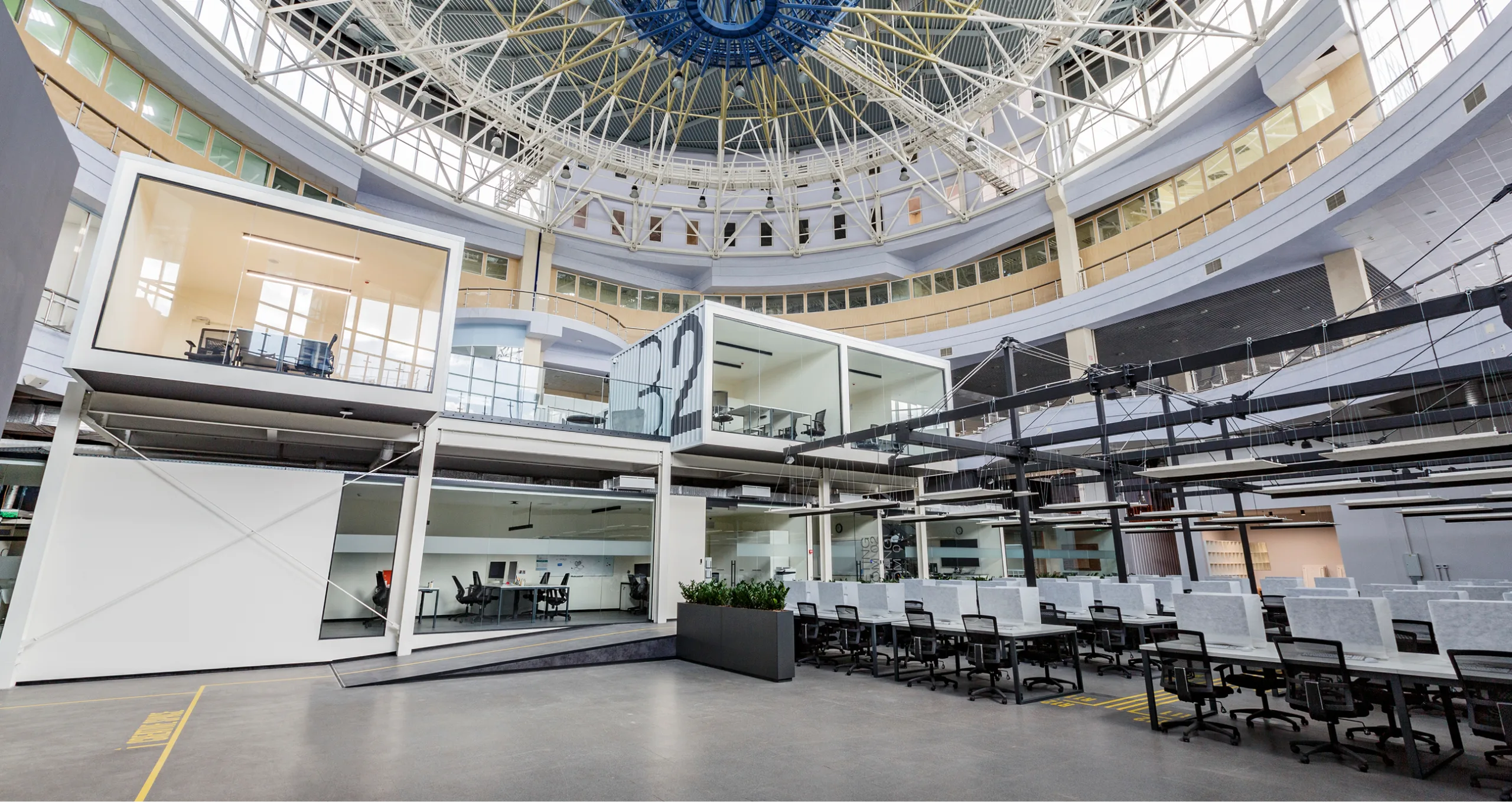 Vue d'un espace de bureau, avec une aire ouverte et des bureaux vitrés et fermés, dans un espace contemporain.