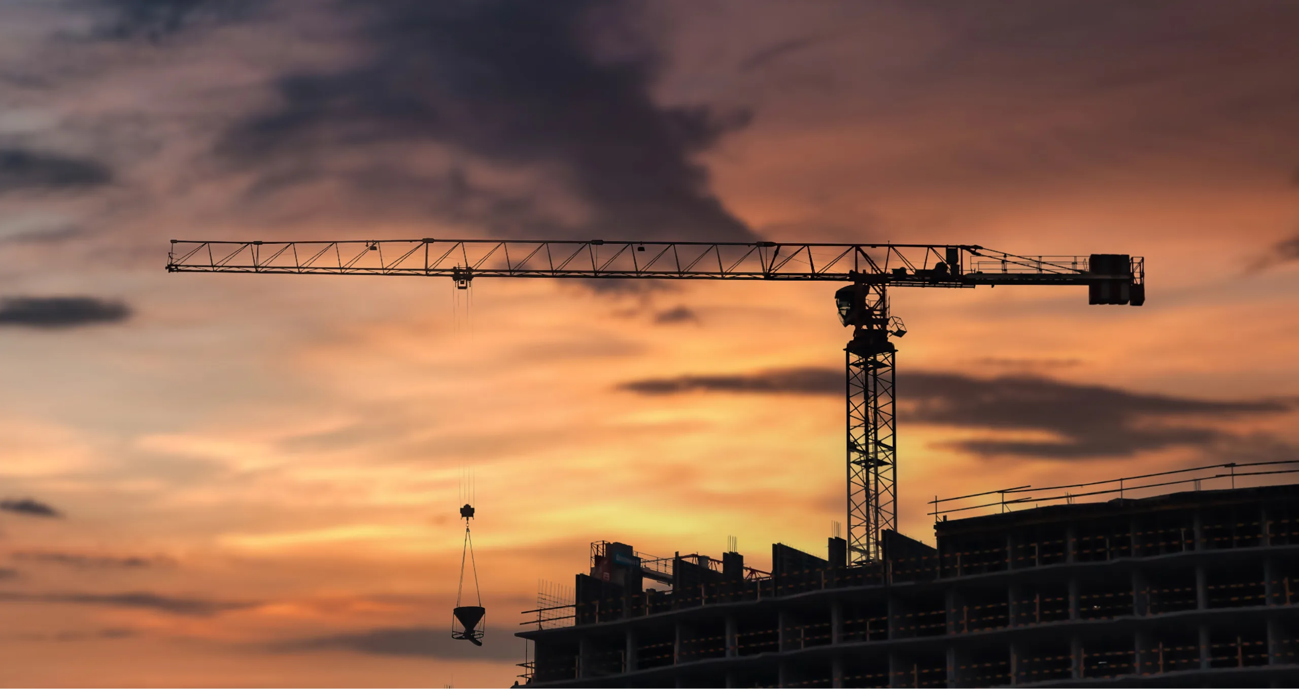 Couché de soleil avec une grue et un immeuble en construction en avant-plan