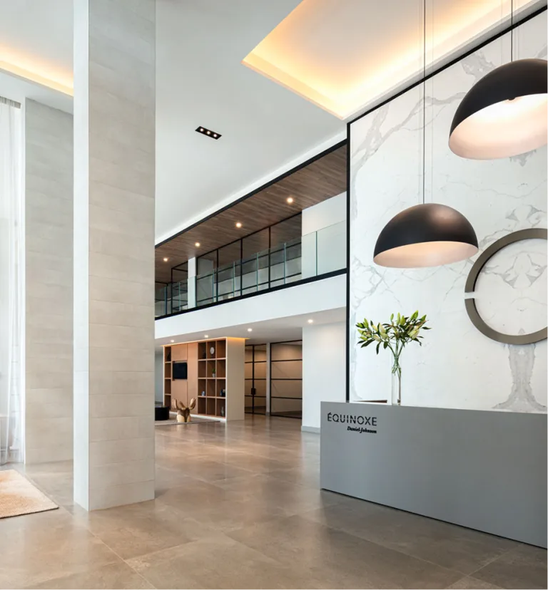 Vue du lobby du Équinoxe Daniel Johnson avec le logo de celui-ci au mur, derrière le comptoir.