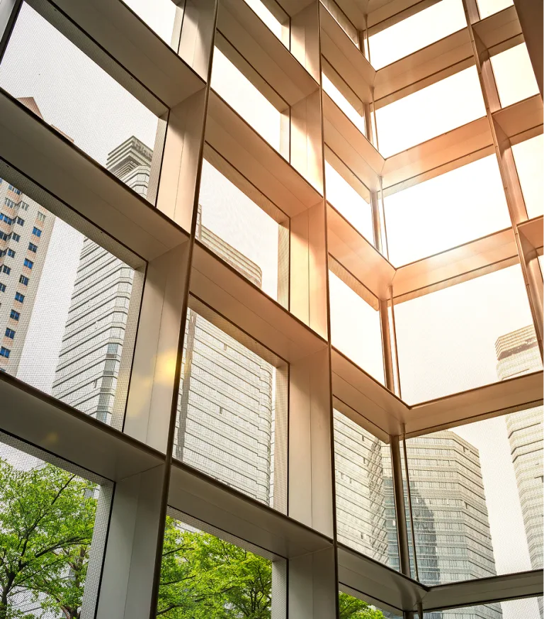 Interior of a modern office building, with a view of other buildings and trees.